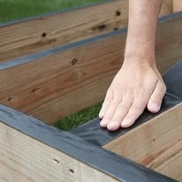 Hand applying joist flashing tape to deck framing