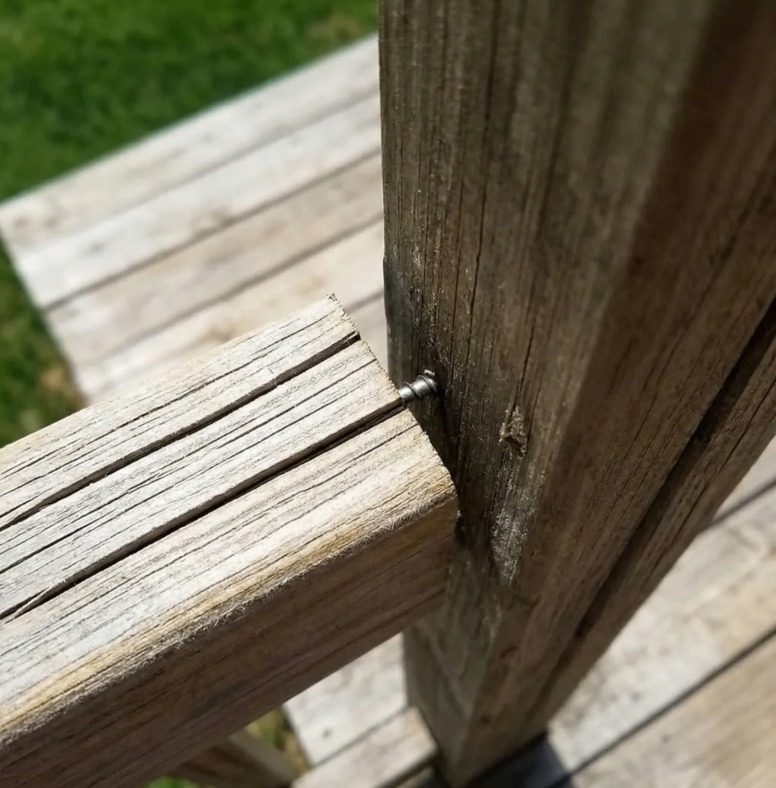 Close-up of popped fastener on weathered deck railing